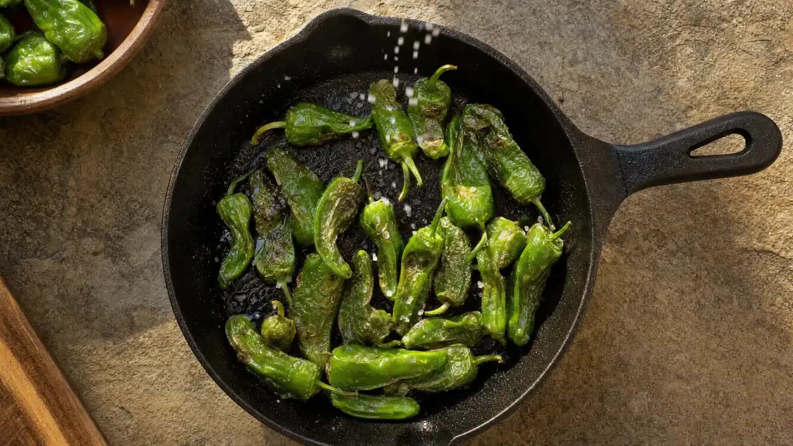 Pimientos de Padrón fritos con sal gruesa en una sartén de hierro